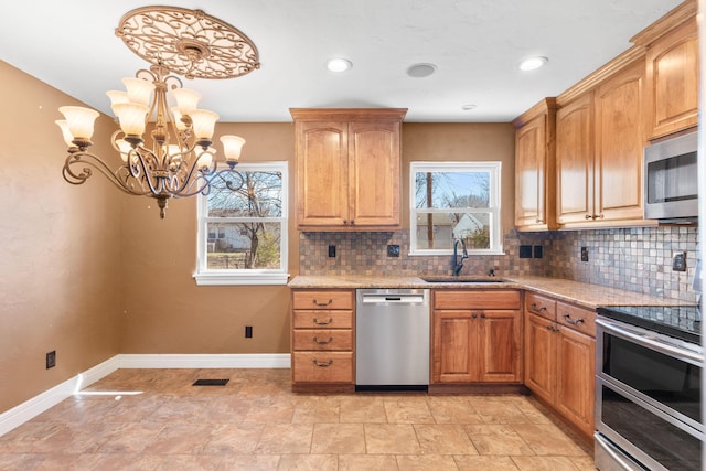 kitchen featuring baseboards, visible vents, a sink, stainless steel appliances, and tasteful backsplash