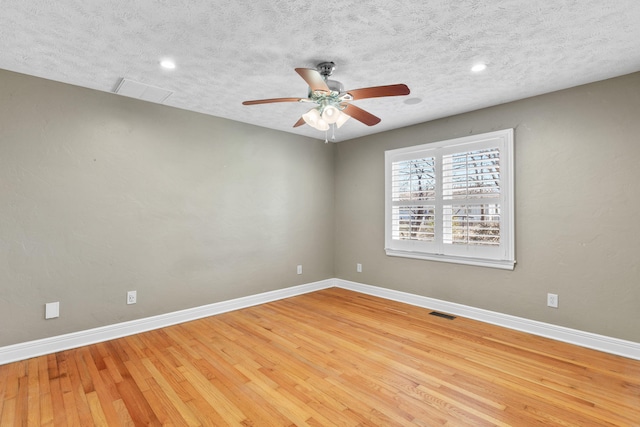 unfurnished room with visible vents, a textured ceiling, baseboards, and wood finished floors