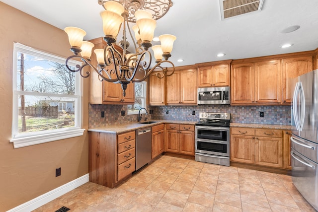 kitchen featuring visible vents, decorative backsplash, brown cabinets, stainless steel appliances, and a sink