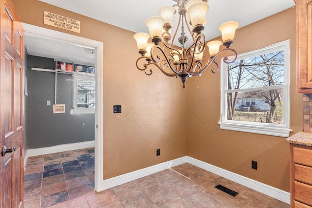 dining area with stone finish floor, a notable chandelier, baseboards, and visible vents