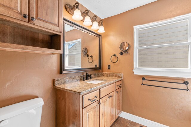 half bathroom featuring baseboards, toilet, vanity, and tile patterned flooring