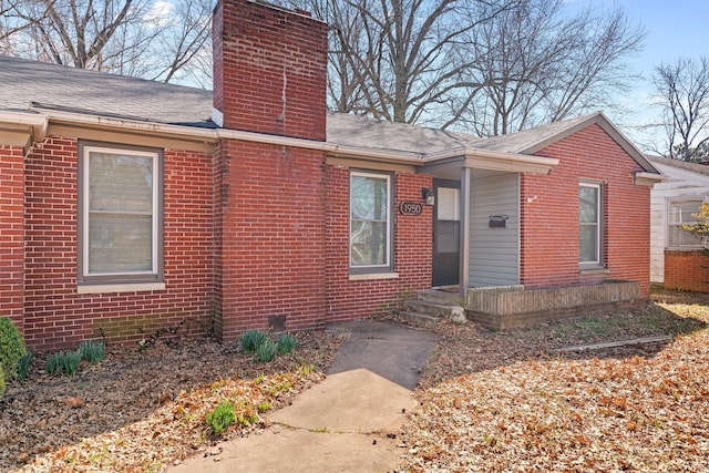 view of front of property featuring brick siding, roof with shingles, and a chimney