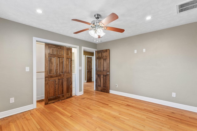 unfurnished bedroom with visible vents, a textured ceiling, baseboards, and light wood-style floors