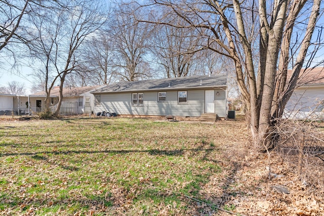 back of house with entry steps, a lawn, and fence