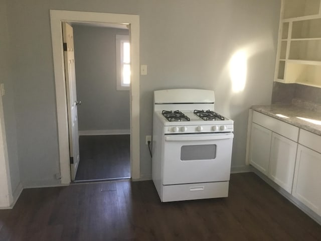 kitchen with baseboards, white range with gas stovetop, light countertops, dark wood-style floors, and white cabinetry