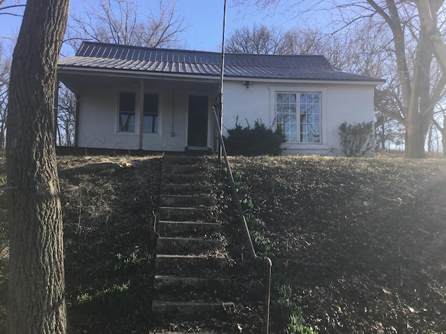 view of front facade featuring metal roof, covered porch, and stucco siding