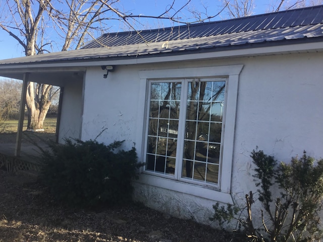 view of side of home featuring metal roof and stucco siding