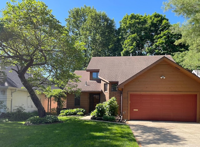 view of front of house with a front yard, roof with shingles, concrete driveway, a garage, and brick siding