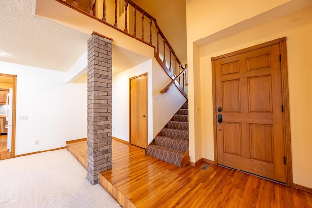 entrance foyer with stairway, baseboards, ornate columns, and wood finished floors