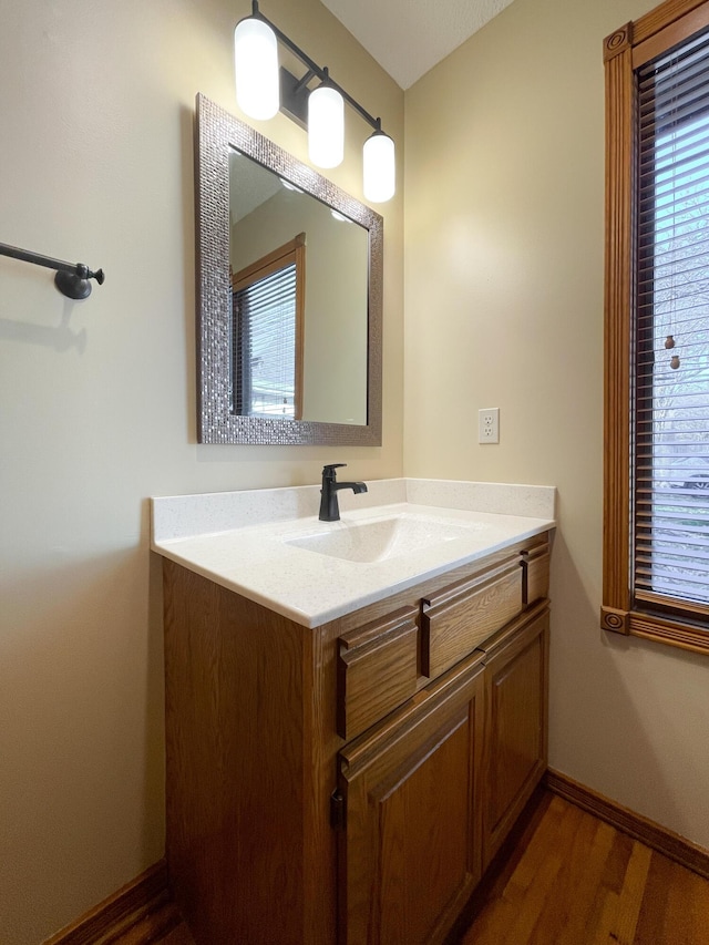 bathroom with a wealth of natural light, baseboards, wood finished floors, and vanity