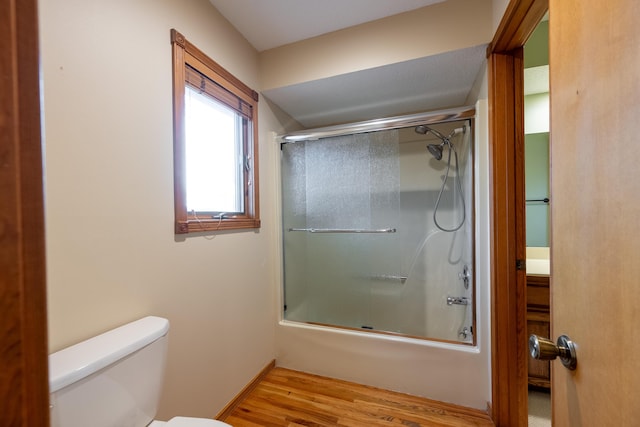 full bath featuring enclosed tub / shower combo, toilet, and wood finished floors