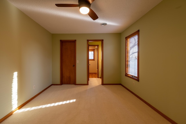 unfurnished bedroom with visible vents, ceiling fan, baseboards, light carpet, and a textured ceiling