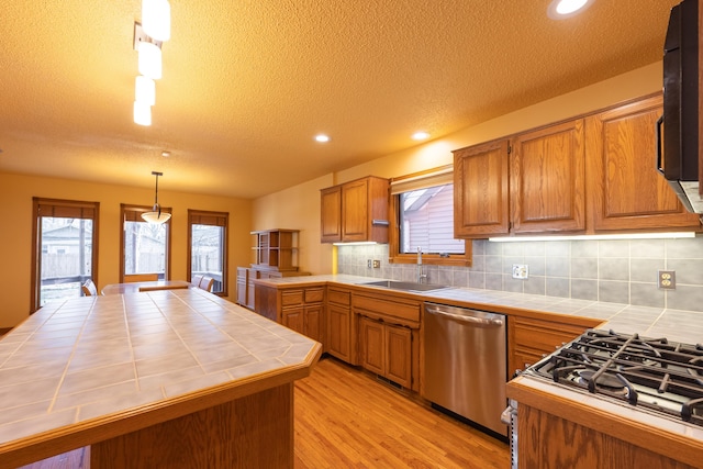 kitchen featuring tile countertops, dishwasher, a healthy amount of sunlight, and a sink