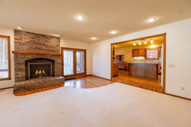 unfurnished living room with a fireplace, a healthy amount of sunlight, and light carpet