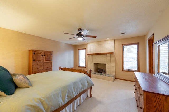 bedroom with visible vents, a textured ceiling, a fireplace, baseboards, and light colored carpet