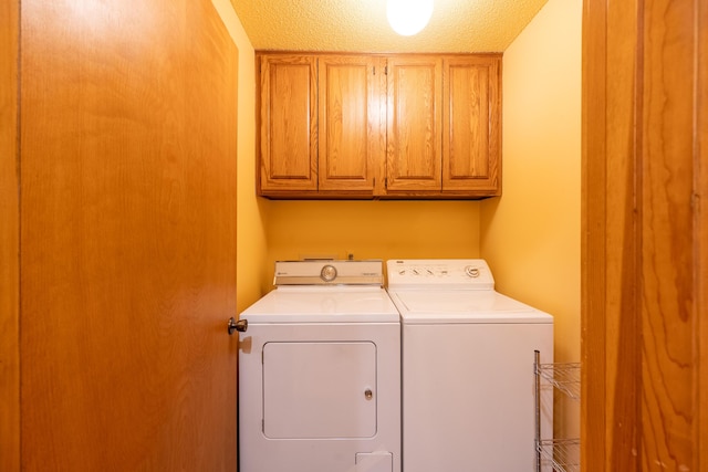 washroom with washing machine and clothes dryer, cabinet space, and a textured ceiling