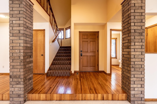 entrance foyer featuring stairway, a high ceiling, ornate columns, and wood-type flooring