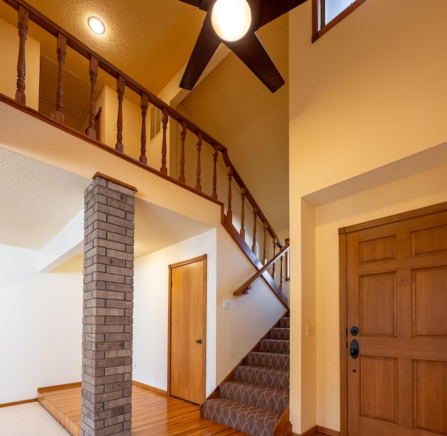 foyer entrance featuring wood finished floors, baseboards, a high ceiling, decorative columns, and stairs