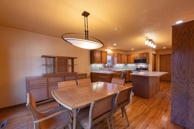 dining space featuring light wood-style flooring, recessed lighting, baseboards, and a textured ceiling