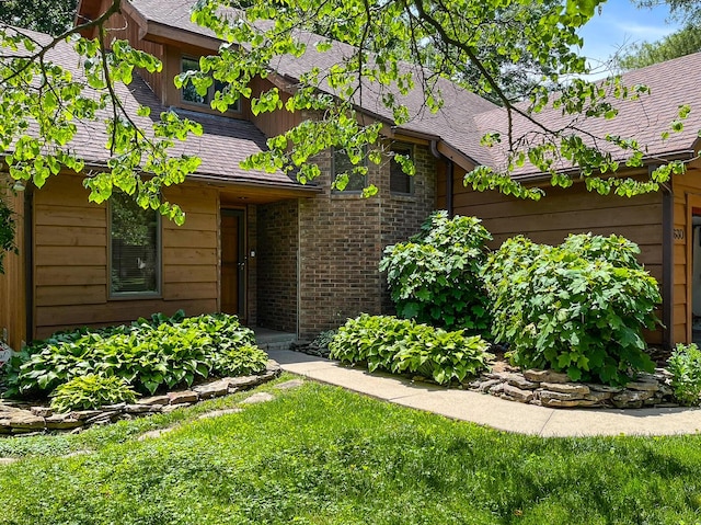 entrance to property with brick siding and roof with shingles