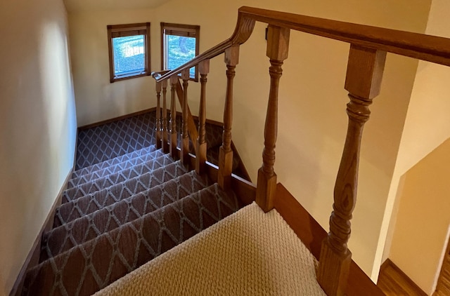 stairway featuring baseboards and carpet floors