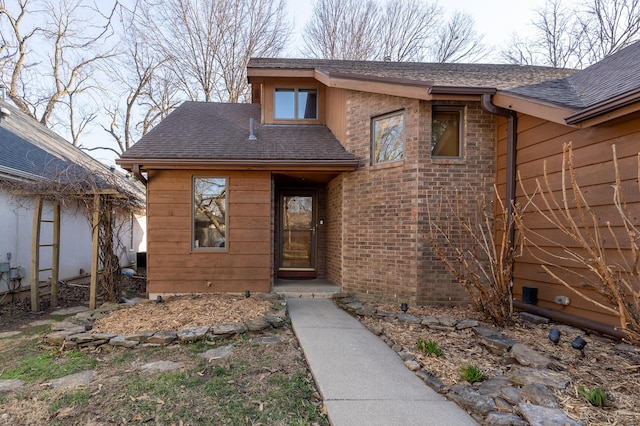 view of front facade with brick siding and a shingled roof