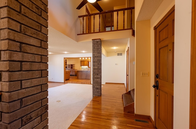 hallway featuring visible vents, baseboards, wood finished floors, and ornate columns