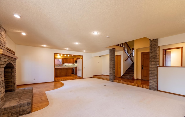 unfurnished living room featuring recessed lighting, a fireplace, a textured ceiling, and stairs