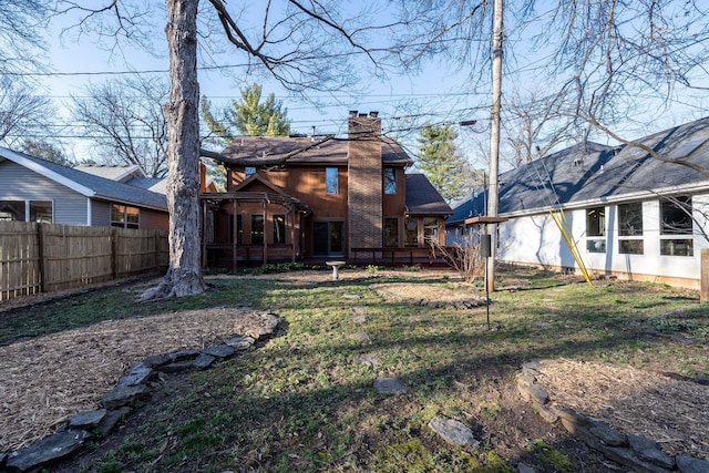 back of property with fence, a sunroom, a chimney, a yard, and a deck