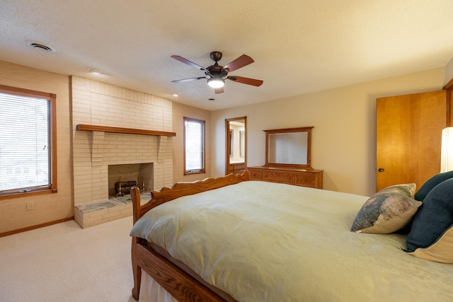 bedroom with visible vents, a ceiling fan, baseboards, light colored carpet, and a brick fireplace