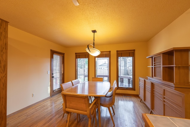 dining space featuring light wood finished floors, visible vents, and a textured ceiling