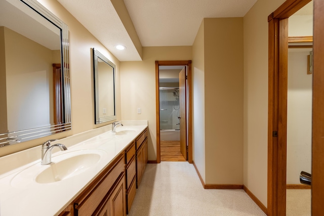 full bathroom featuring double vanity, shower / bath combination with glass door, baseboards, and a sink