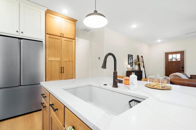 kitchen with open floor plan, high end fridge, light stone countertops, and a sink