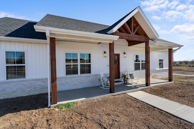 view of front of property featuring brick siding and roof with shingles