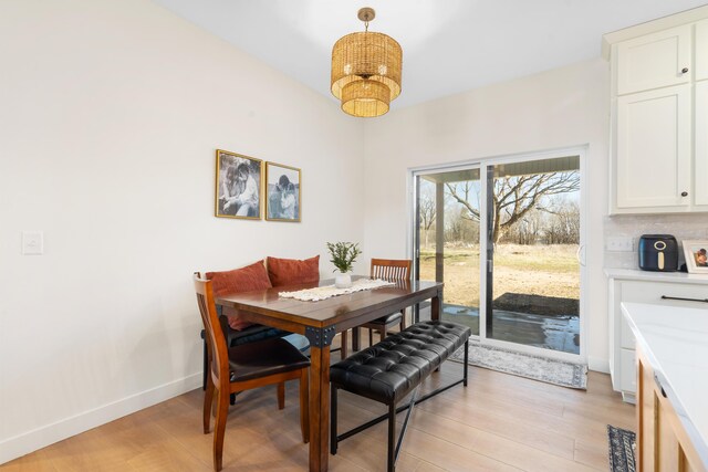 dining space featuring baseboards, light wood-style floors, and an inviting chandelier