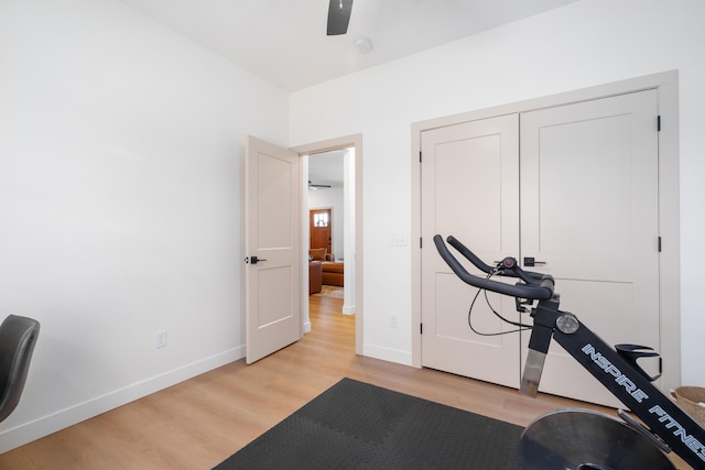 workout area with light wood-style flooring, baseboards, and ceiling fan