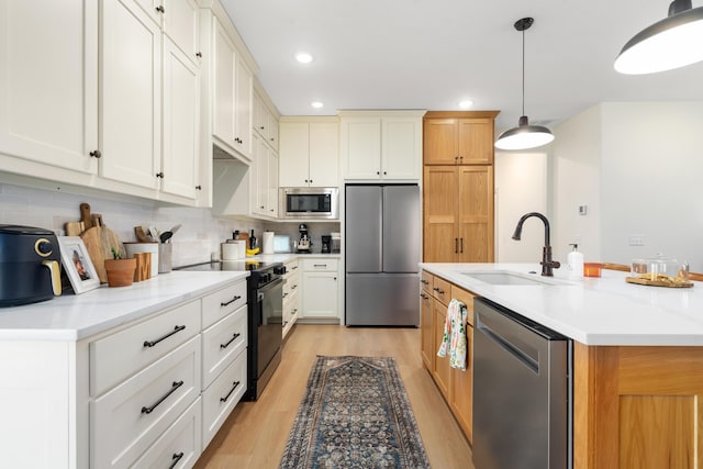 kitchen featuring light wood-style flooring, a sink, decorative light fixtures, stainless steel appliances, and decorative backsplash