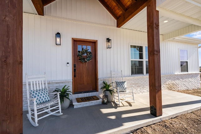 entrance to property featuring brick siding and covered porch