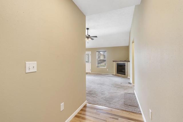 hall featuring light wood finished floors, light carpet, and baseboards