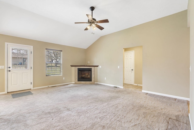 unfurnished living room featuring vaulted ceiling, light colored carpet, a high end fireplace, and ceiling fan