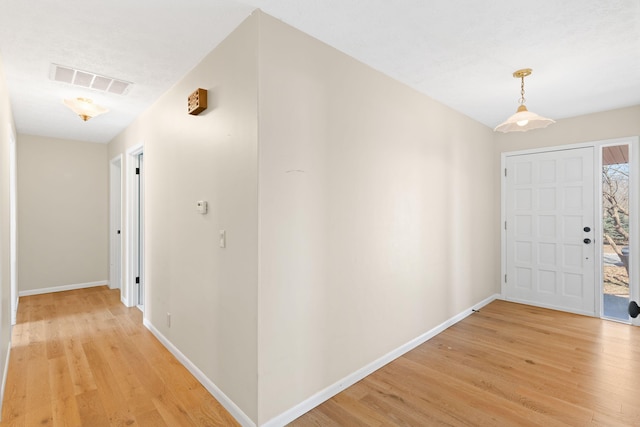 foyer with light wood-style floors, visible vents, and baseboards