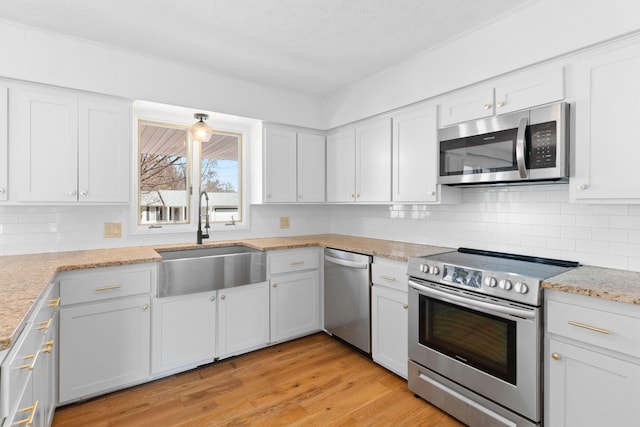 kitchen with light wood-style flooring, white cabinets, stainless steel appliances, and a sink