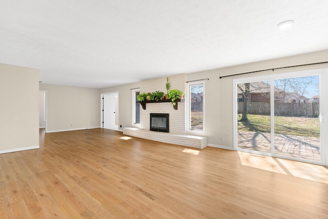 unfurnished living room featuring baseboards, light wood-style floors, and a fireplace