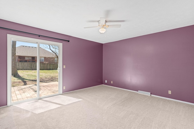 carpeted spare room featuring visible vents, ceiling fan, and baseboards