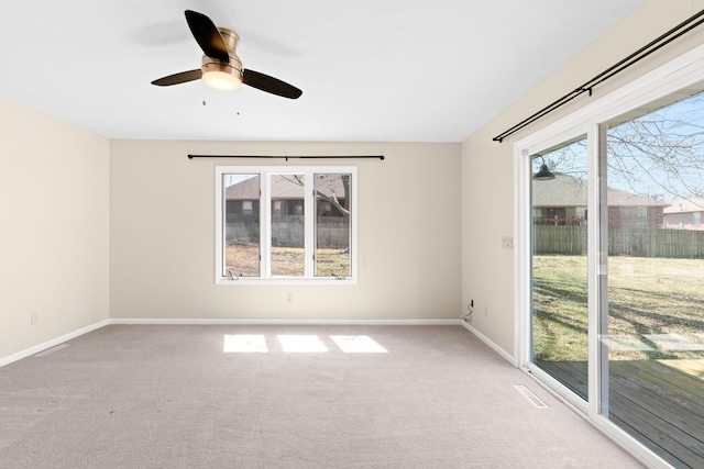 spare room with ceiling fan, baseboards, and light carpet