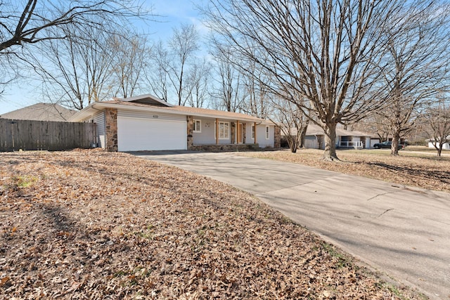 ranch-style home featuring stone siding, driveway, an attached garage, and fence