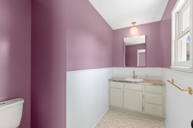 half bath featuring a wainscoted wall, toilet, and vanity