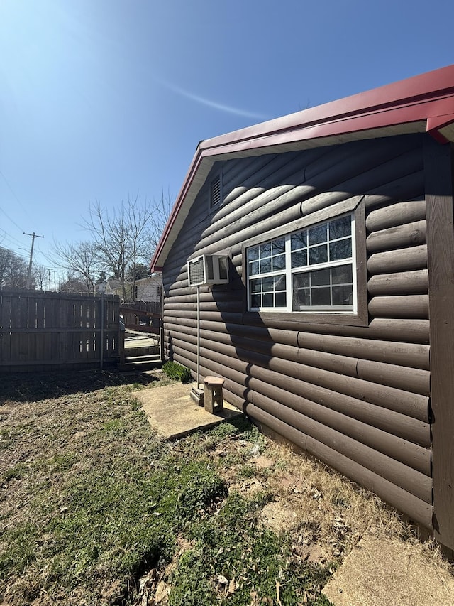 view of side of property with faux log siding and fence