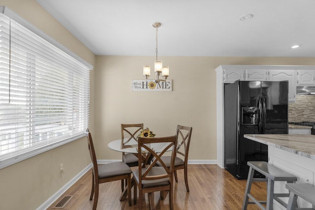 dining room featuring a notable chandelier, light wood-style floors, visible vents, and baseboards