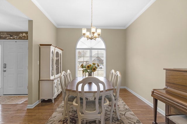 dining space featuring crown molding, a notable chandelier, wood finished floors, and baseboards